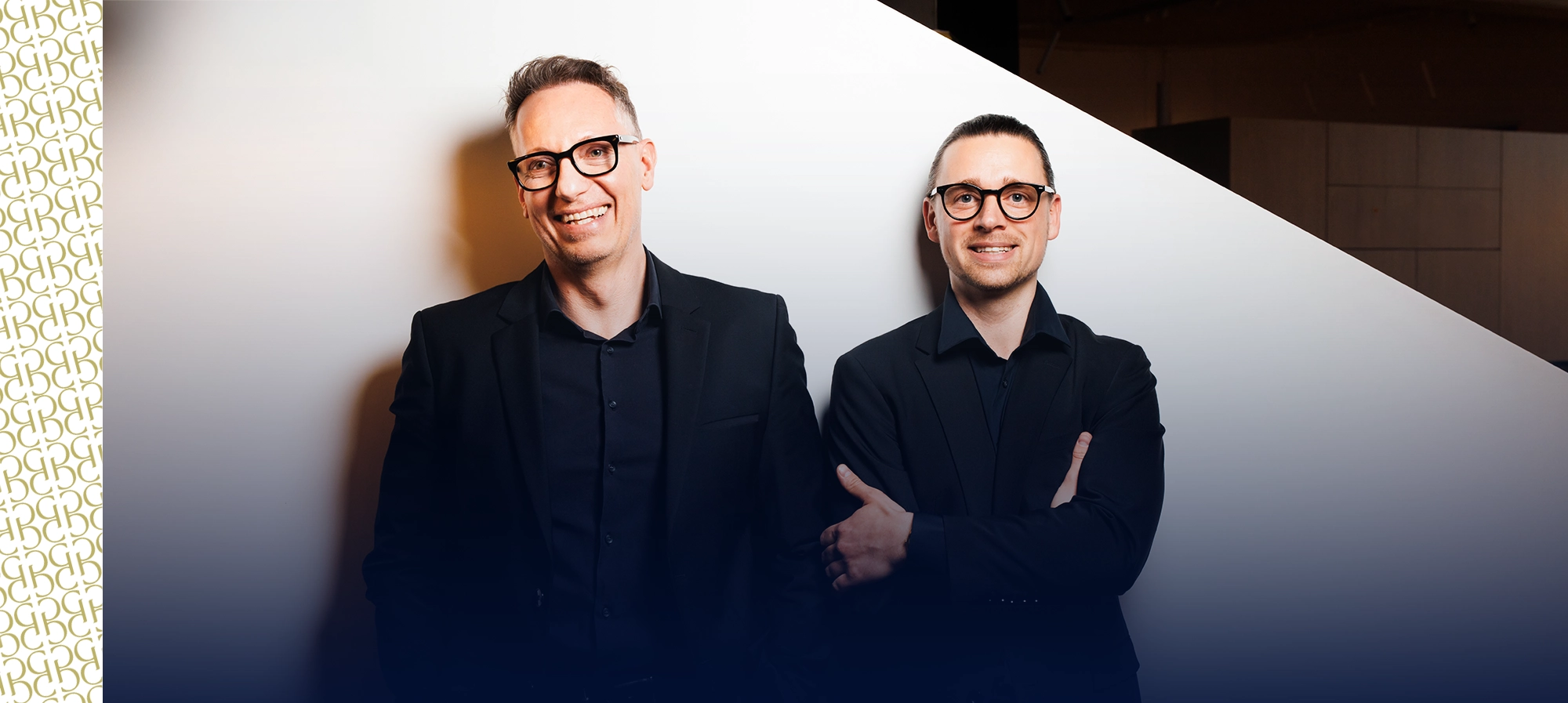 Roman und Georg stehen lächelnd vor einer weißen Wand
